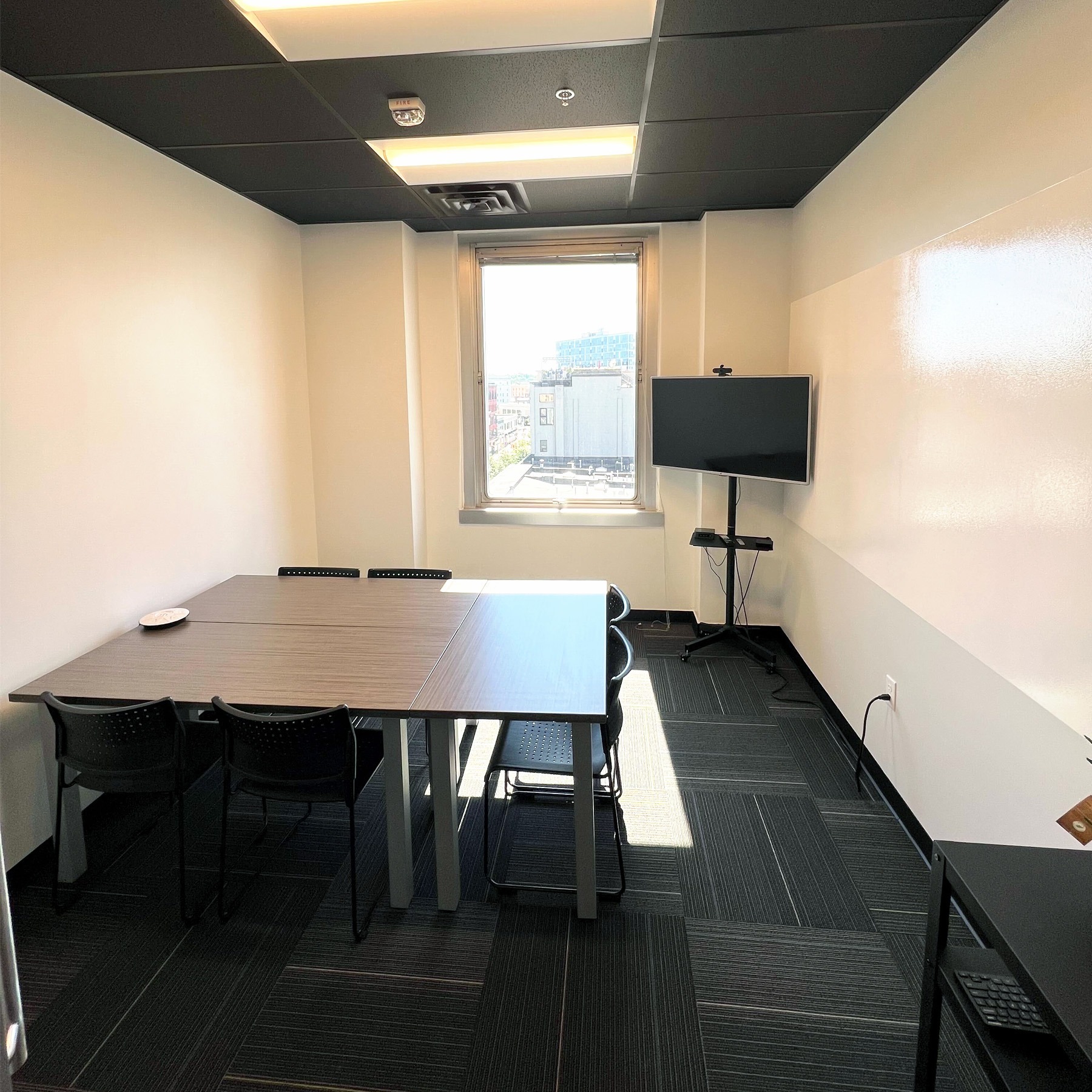 Our Eastown conference room with 3 tables and tv next to a white board wall