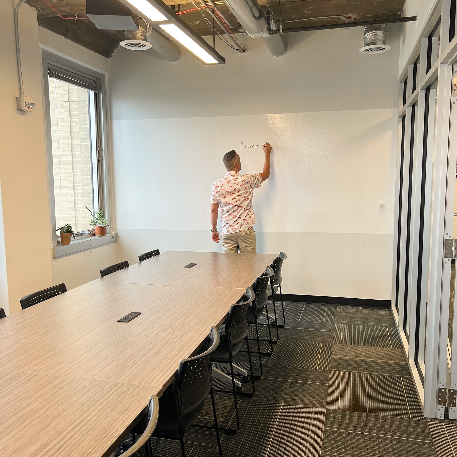 Man writing on the white board wall in the Learning Center conference room